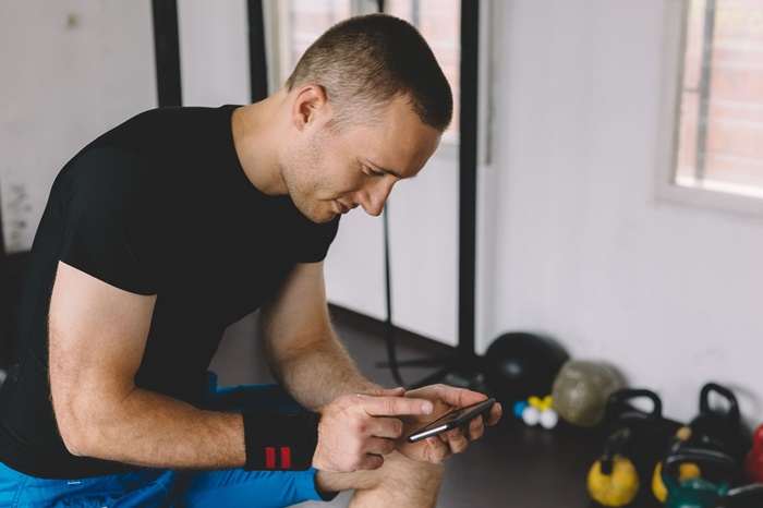 sportsman in the gym texting on smartphone royalty free image 537230860 1546969957